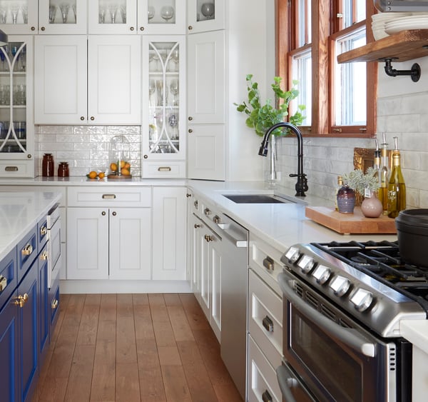 Side view of a French kitchen design by Jasmin Reese: white cabinets, marble countertops, blue island, black drop lights, Chicago. 