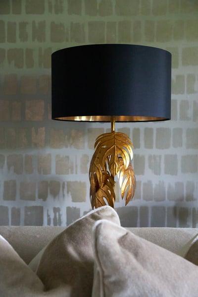 A green gold lamp designed of maple leaves with a circular black lampshade behind a cream sofa - living room design by Jasmin Reese Interiors, Chicago, USA. 