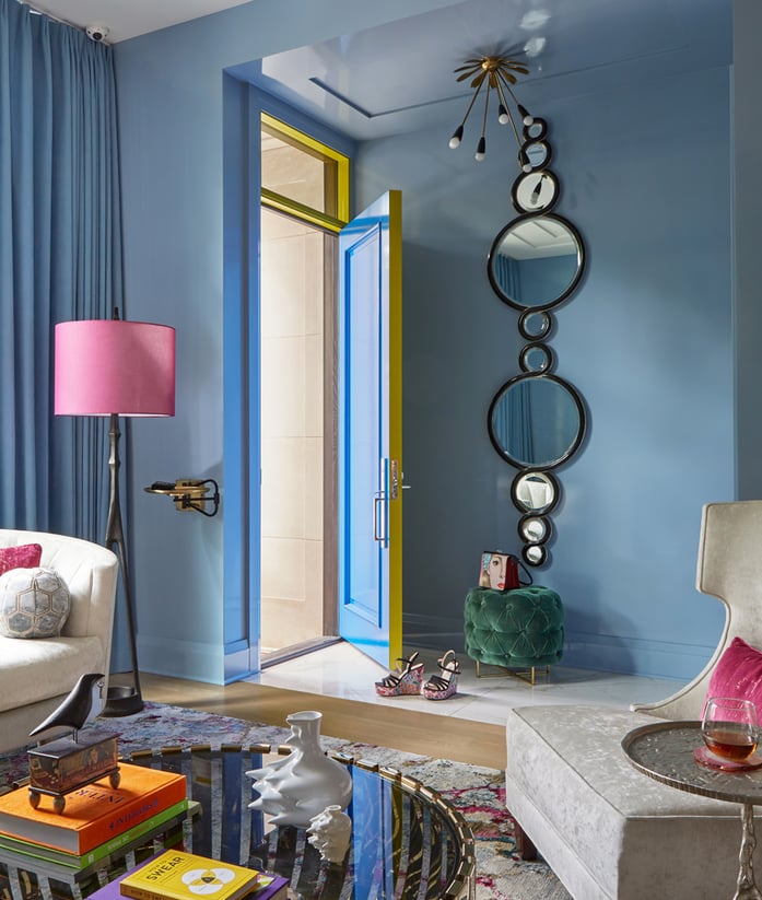 An opened blue door with a circular mirror in detail in a blue living room designed by Jasmin Reese Interiors, Chicago, USA. 