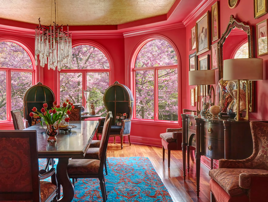 A bright red formal dining room with large Victorian wingback chairs designed by Jasmin Reese, Chicago. 
