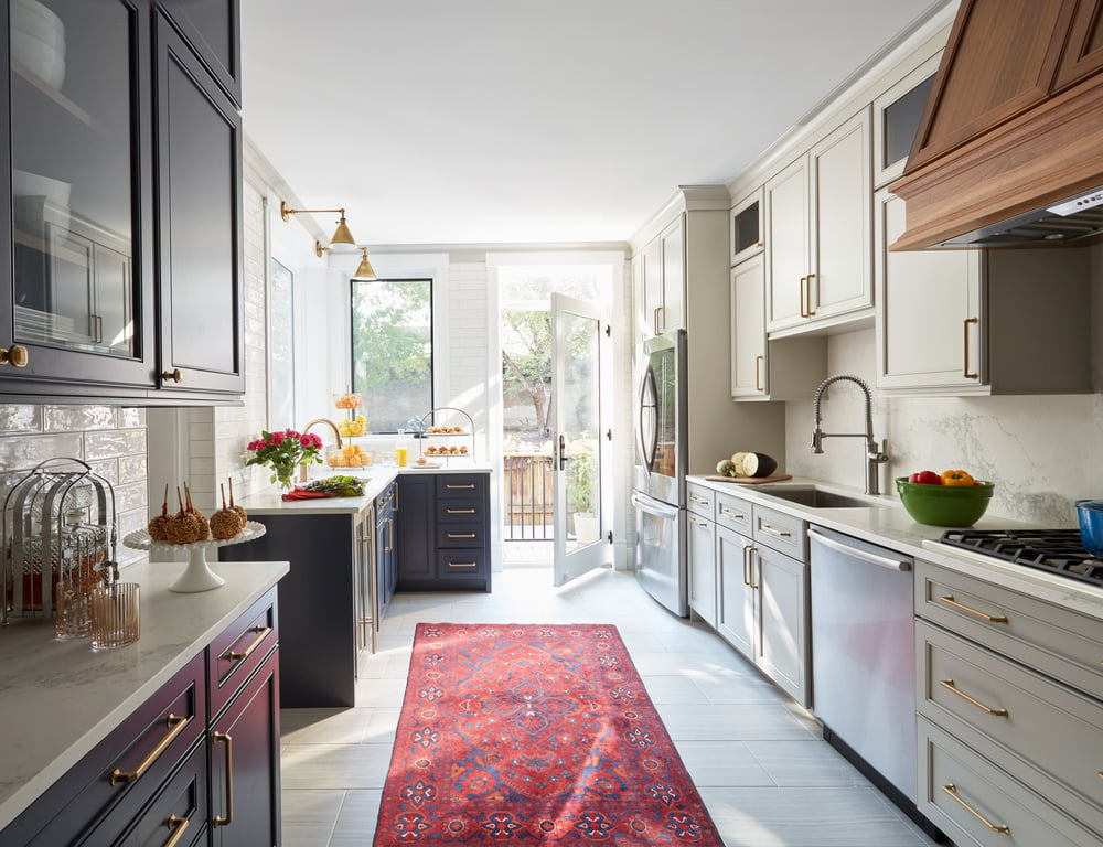 A large bright galley kitchen designed by Jasmin Reese: red Persian runner, marble flooring and countertops, Chicago.