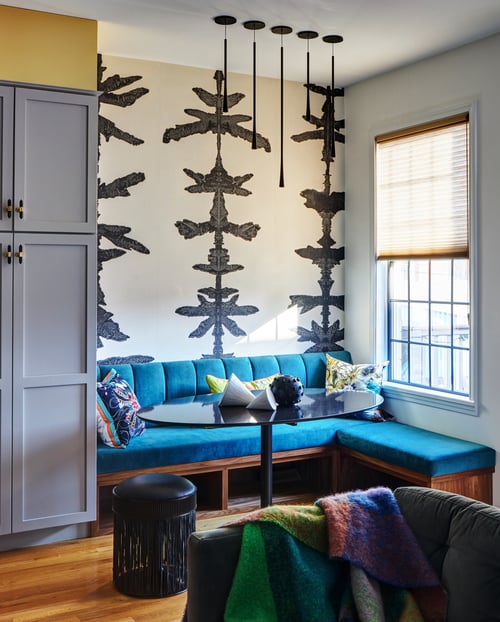 An intimate dining room area designed by Jasmin Reese with blue velvet booth seating and ink blot wallpaper, Chicago. 
