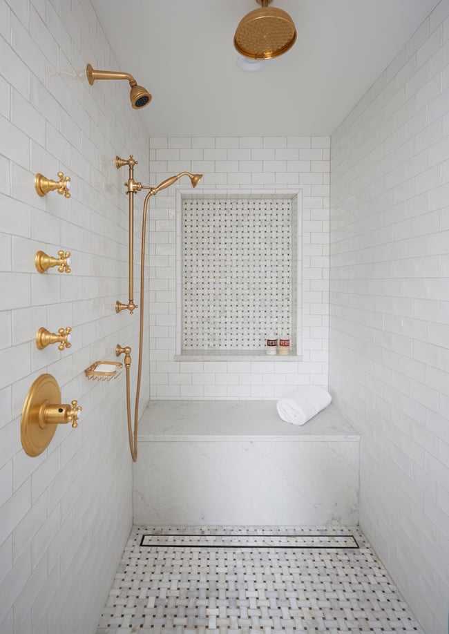 A sauna-style walk-in shower with rose gold fixtures and marble designed by Jasmin Reese, Chicago.