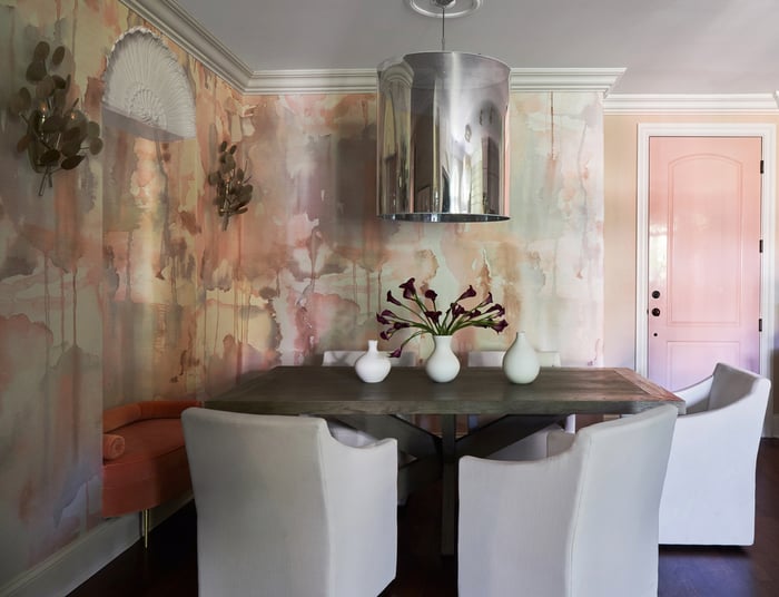 A dining room designed by Jasmin Reese with a large silver cylindrical chandelier and inset seating on one side, Chicago. 