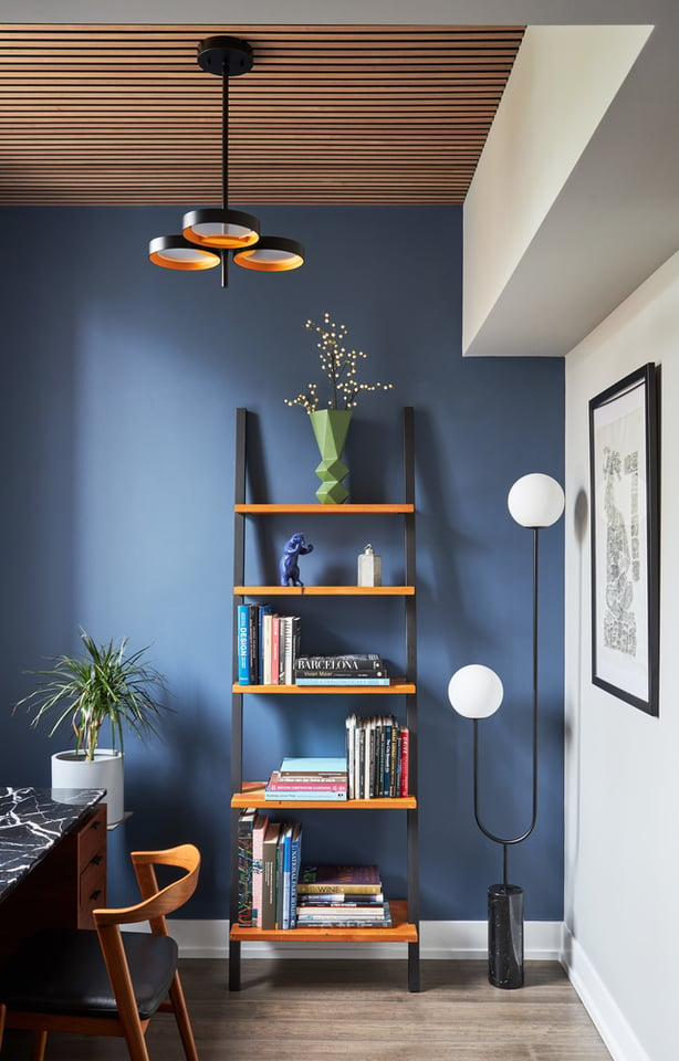 Ladder bookshelf in a small home office designed by Jasmin Reese, Chicago: black, white, blue details. 