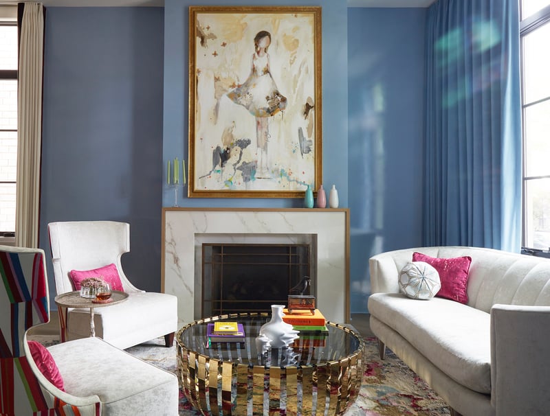 A modern living room with low wing-back chairs highlighting a light blue room with a modernist fireplace, large portrait art, and a metal and glass coffee table. The focal point is on the portrait of a young girl - living room design by Jasmin Reese Interiors, Chicago, USA. 