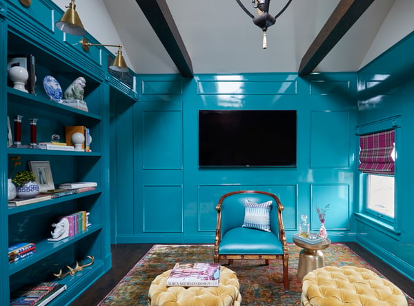 A living room painted in turquoise paint with a slick, shiny finish with a turquoise leather armchair and gold pin cushion ottomans - living room design by Jasmin Reese Interiors, Chicago, USA. 