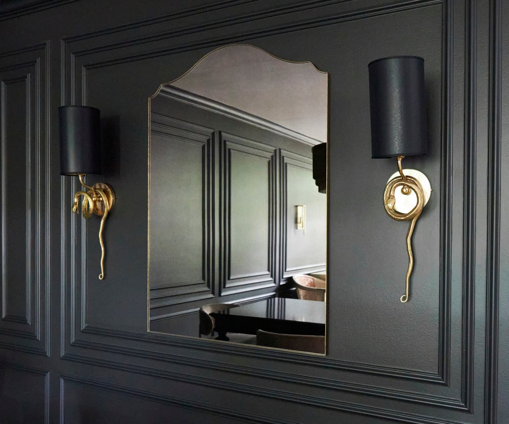 A large mirror with gold serpent wall sconces on either side - dining room design by Jasmin Reese, Chicago. 