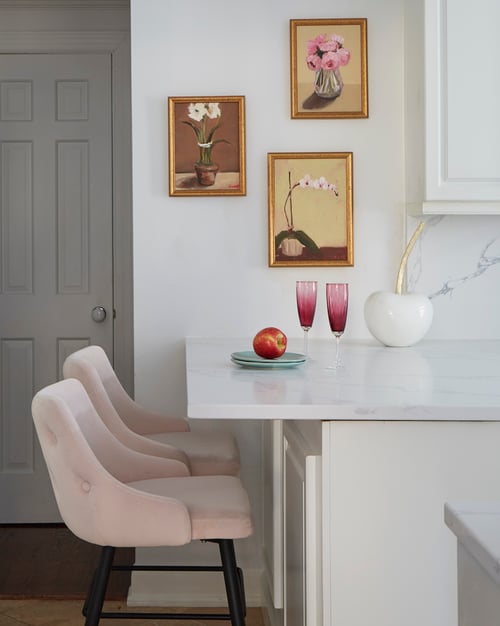 A small dining room area designed by Jasmin Reese: two pink velvet bar stools by a marble top counter, Chicago. 