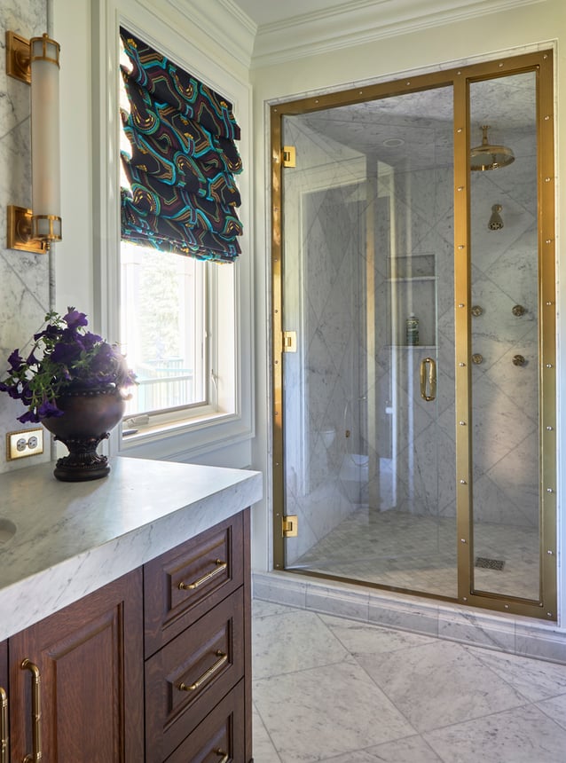 A large walk-in shower in a bathroom designed by Jasmin Reese with glass, brass, and marble, Chicago. 