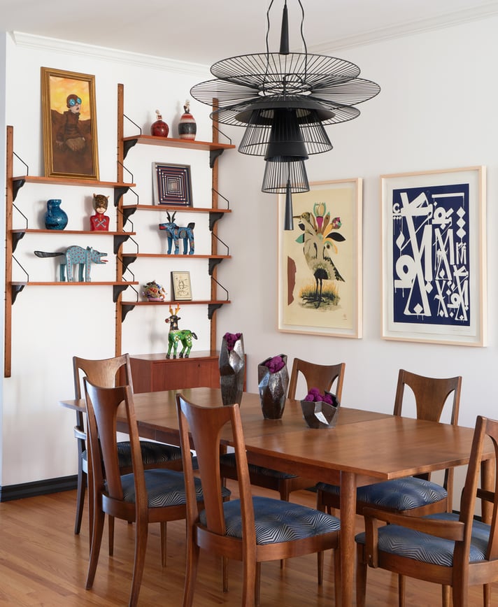 A modernist dining room designed by Jasmin Reese with pop and rustic art on minimalist shelves, Chicago. 