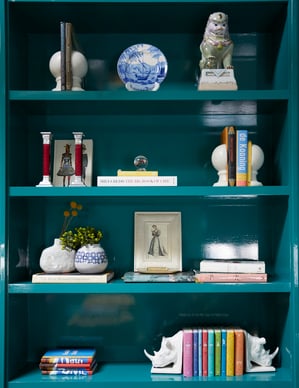 A bookshelf painted turquoise with a slick finish with books and art - living room design by Jasmin Reese Interiors, Chicago, USA. 