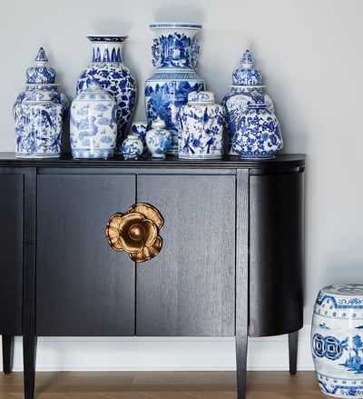 An antique sideboard in dark wood with a poppy design fixture in pink gold with a collection of antique blue and white Chinese vases in different sizes on top - living room design by Jasmin Reese Interiors, Chicago, USA. 