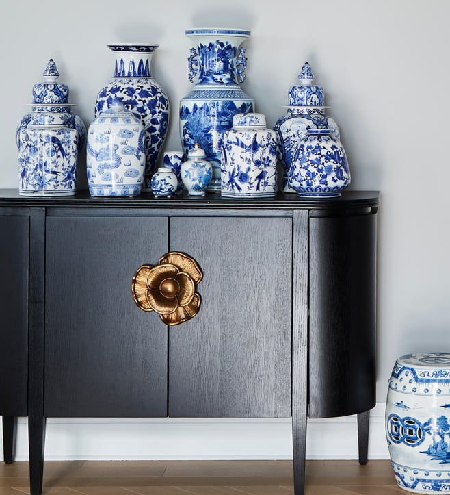 An antique sideboard in dark wood with a poppy design fixture in pink gold with a collection of antique blue and white Chinese vases in different sizes on top - living room design by Jasmin Reese Interiors, Chicago, USA. 
