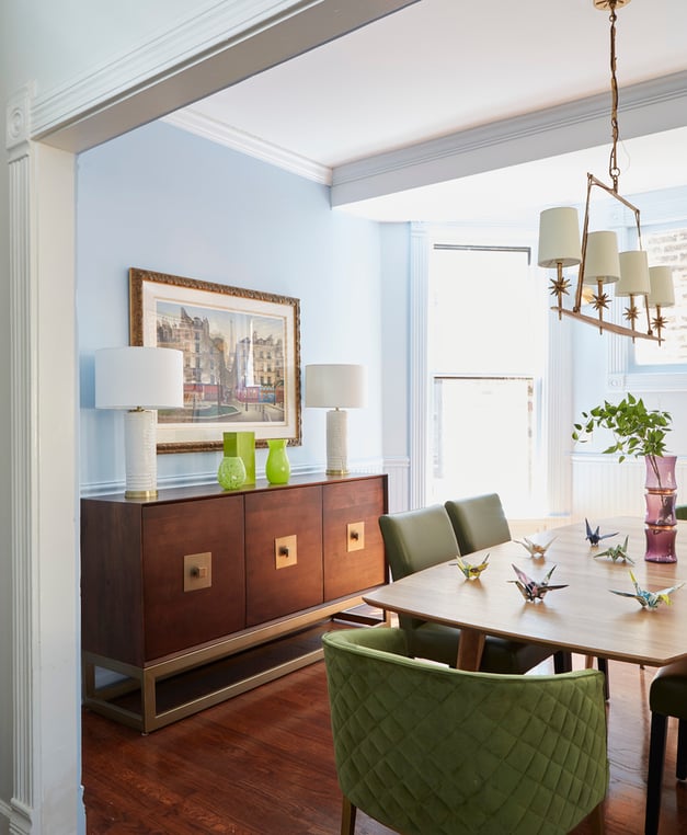A modernist dining room design by Jasmin Reese: large sideboard powder blue walls with green chairs, Chicago. 
