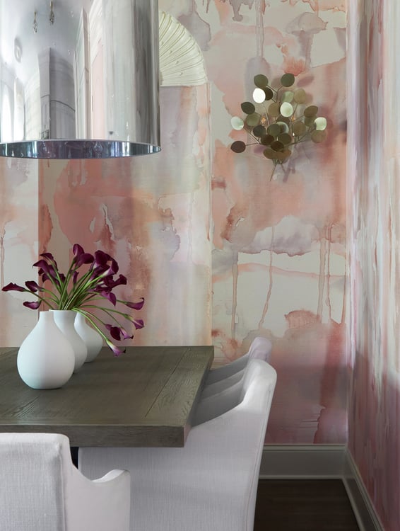 A dining room design by Jasmin Reese with abstract peach and gray wallpaper and metallic art, Chicago. 