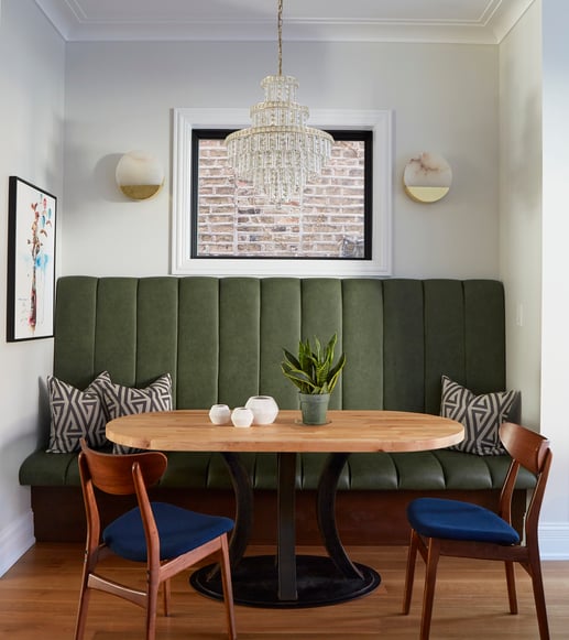 A dining room design by Jasmin Reese with a large plush green booth seat and chandelier, Chicago. 
