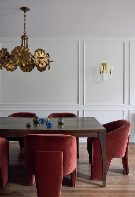 A dining room design by Jasmin Reese with red circular chairs and unique floral chandelier, Chicago. 