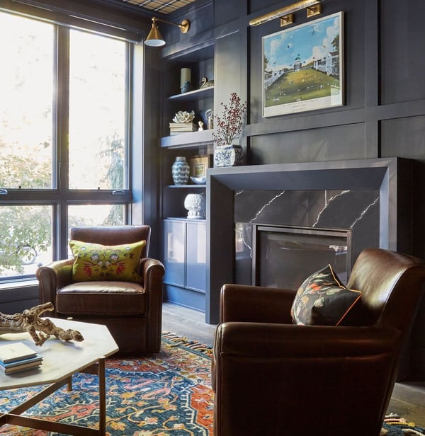 Leather chairs in front of a black matte & black marble fireplace with large full length windows providing natural light design by Jasmin Reese Interiors, Chicago, USA. 
