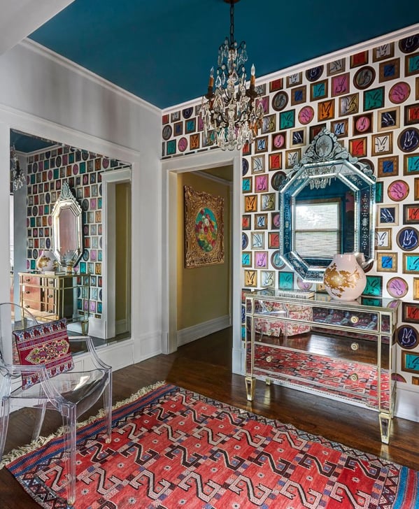 An entry hall with mirrors on all walls and a mirrored chest with drawers, a clear acrylic chair, a red rug, and wallpaper with framed bunnies - living room design by Jasmin Reese Interiors, Chicago, USA.