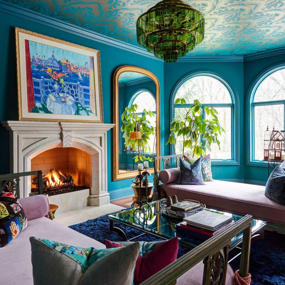 A side view of a large Moroccan-style living room in pink, blue, and turquoise with a white marble fireplace with a large gold-framed mirror- living room design by Jasmin Reese Interiors, Chicago, USA.