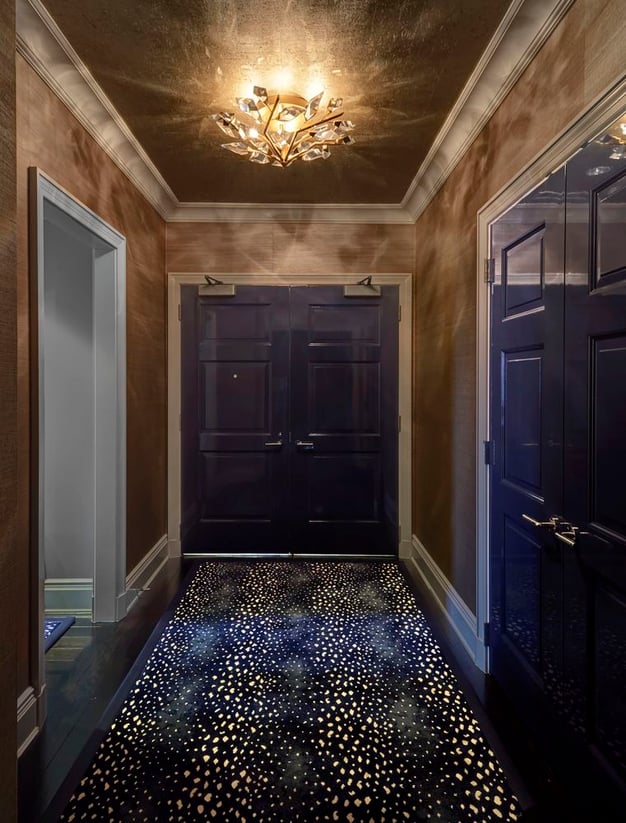 An entry hallway with dark blue double doors with silver fixtures, a long carpet running in dark blue and gold to resemble stars with ceiling lighting to resemble the sun - living room design by Jasmin Reese Interiors, Chicago, USA.