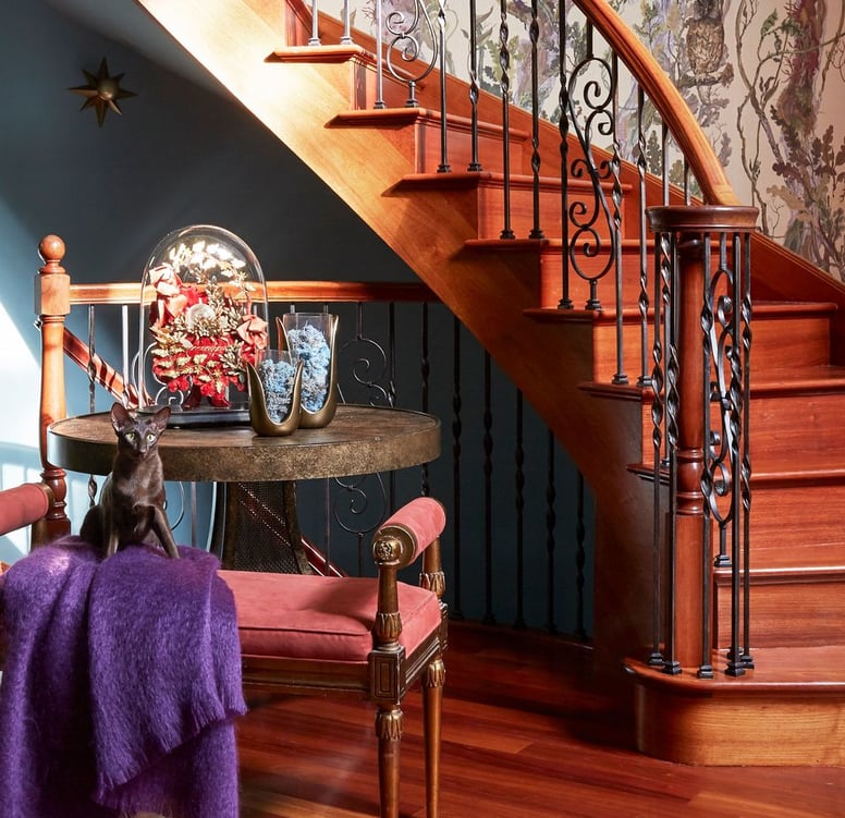 A sitting area on a staircase landing with a settee with a bright purple throw against a delicate iron and wood staircase - living room design by Jasmin Reese Interiors, Chicago, USA. 