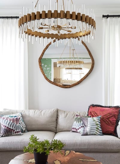 A large cream sofa with colorful pillows beneath a glass and gold art chandelier in a white living room - living room design by Jasmin Reese Interiors, Chicago, USA. 