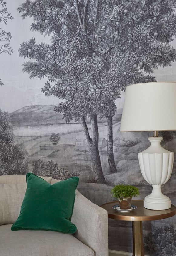 An emerald green velvet accent pillow on a cream sofa with a cream lamp against gray and white olive tree landscape wallpaper - living room design by Jasmin Reese Interiors, Chicago, USA. 