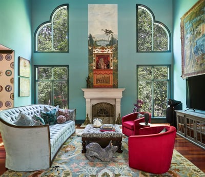 A level view of a large green living room with high ceilings with ornate windows that look out over trees outside - a Victorian sofa is upholstered in light blue to match the muted green tones - living room design by Jasmin Reese Interiors, Chicago, USA. 