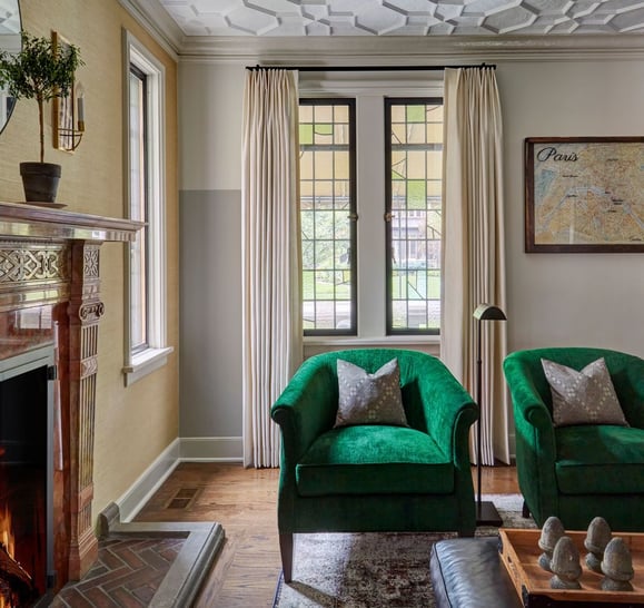 Two bright green velvet circular armchairs beside a fireplace with a traditional, carved mantlepiece - living room design seen in Elle Decor by Jasmin Reese Interiors, Chicago, USA. 