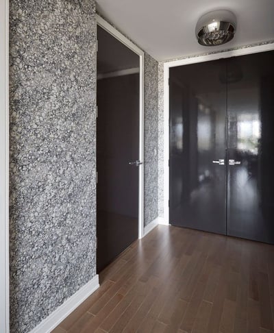 An entryway with hardwood floors, brown metal double doors, grey and white pebble wallpaper, and a chrome chandelier - living room design by Jasmin Reese Interiors, Chicago, USA. 