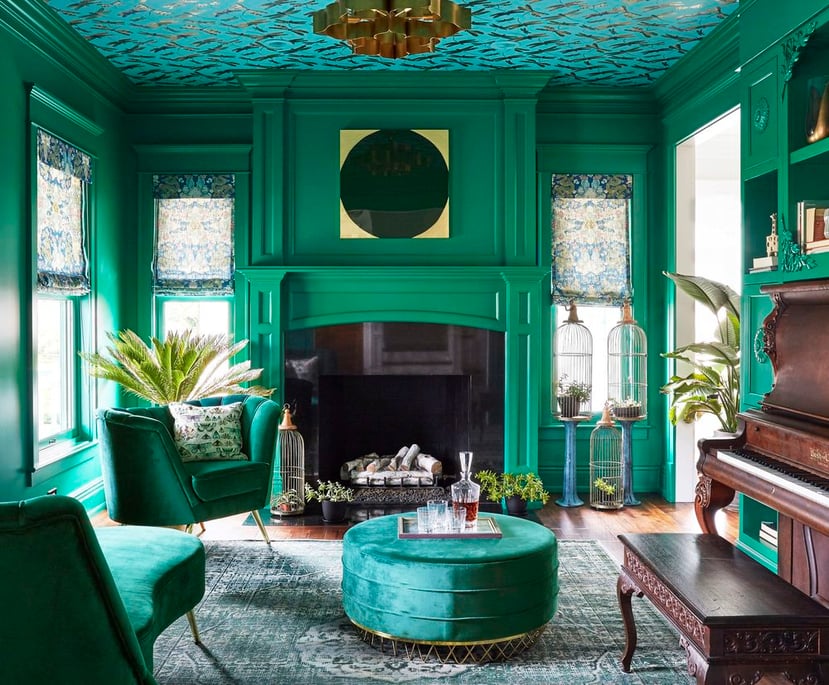An emerald green living room with a large marble and wood fireplace painted green with a gold modern chandelier - designed by Jasmin Reese Interiors, Chicago, USA. 