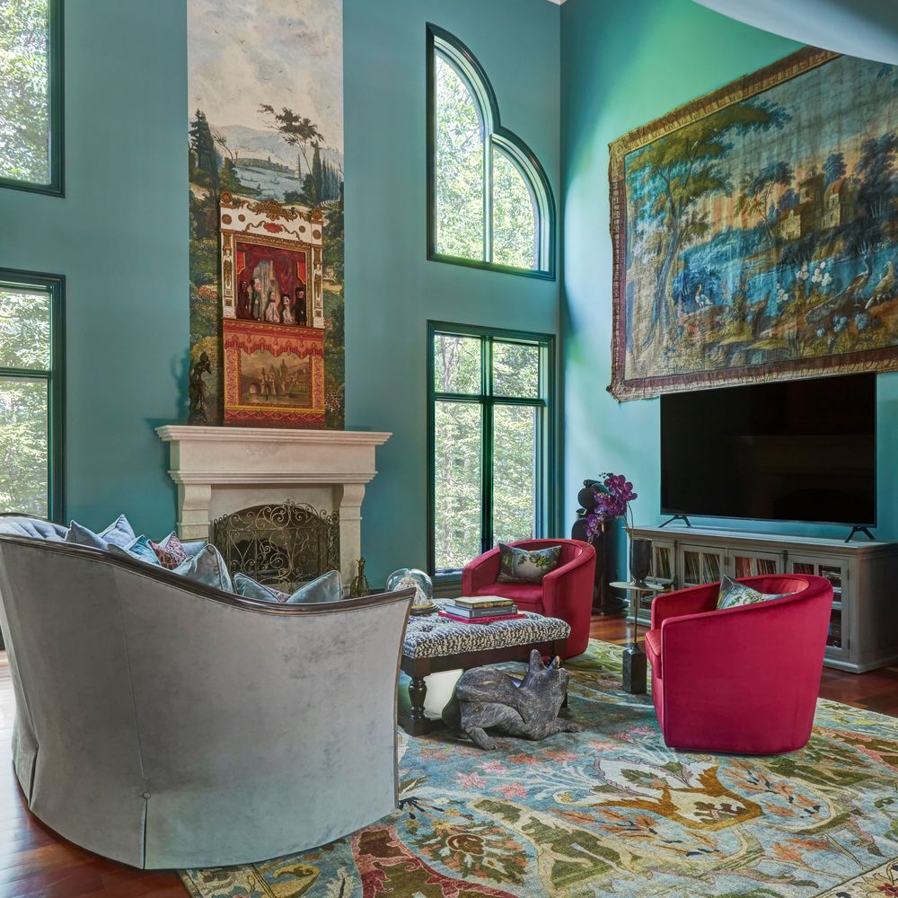  A view of a large green living room with high ceilings with a large antique tapestry behind two raspberry velvet circular armchairs - living room design by Jasmin Reese Interiors, Chicago, USA. 