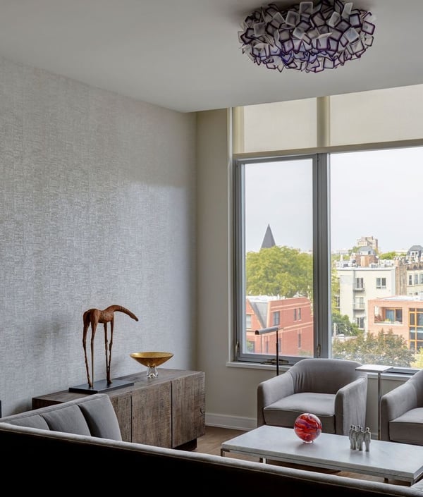 A minimalist living room with a low grey velvet sofa and armchairs with a marble coffee table, and a rough wood sideboard with various art - living room design by Jasmin Reese Interiors, Chicago, USA. 